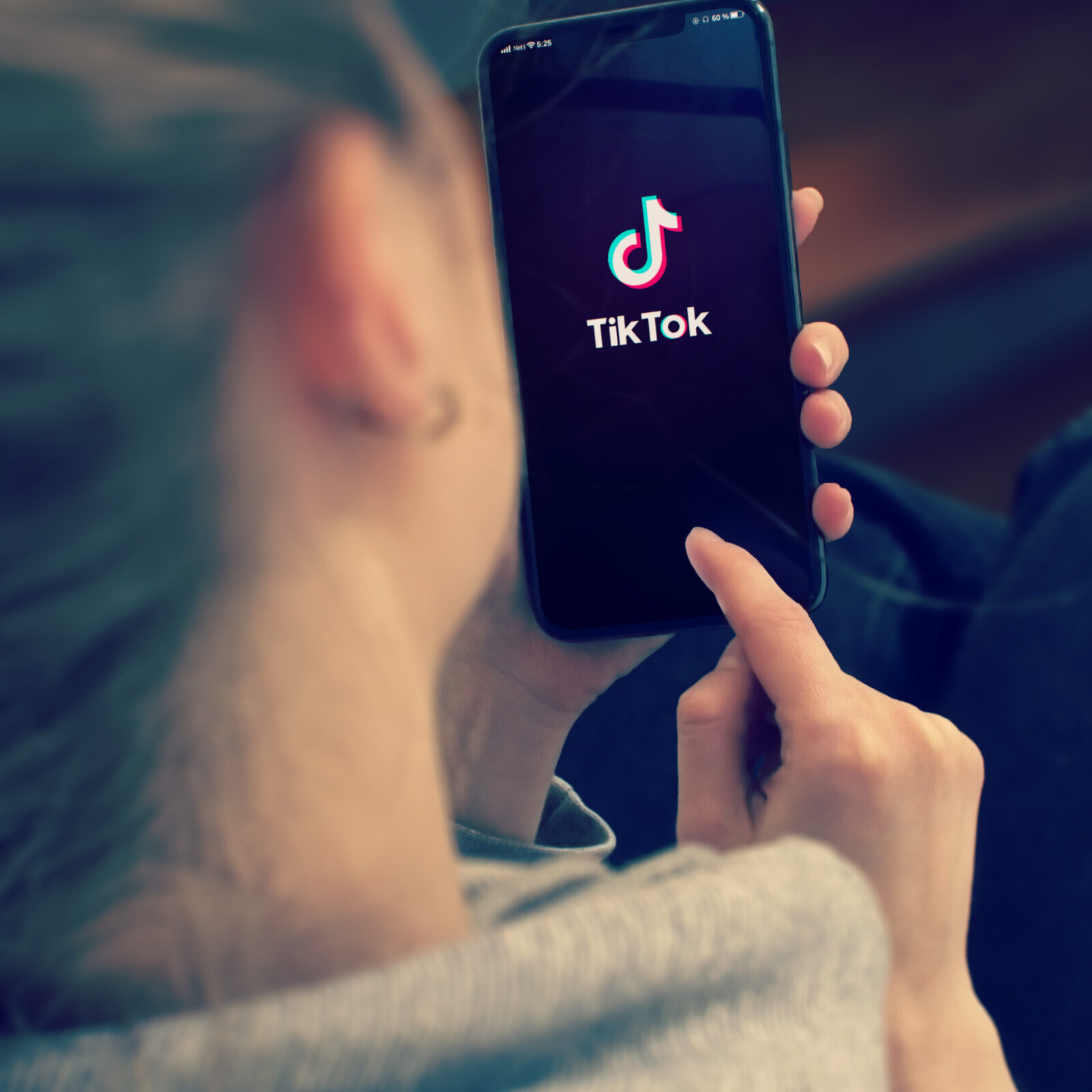 KYIV, UKRAINE-JANUARY, 2020: Tiktok on Smart Phone Screen. Young Girl Pointing or Texting Mobile Phone During a Pandemic Self-Isolation and Coronavirus Prevention.